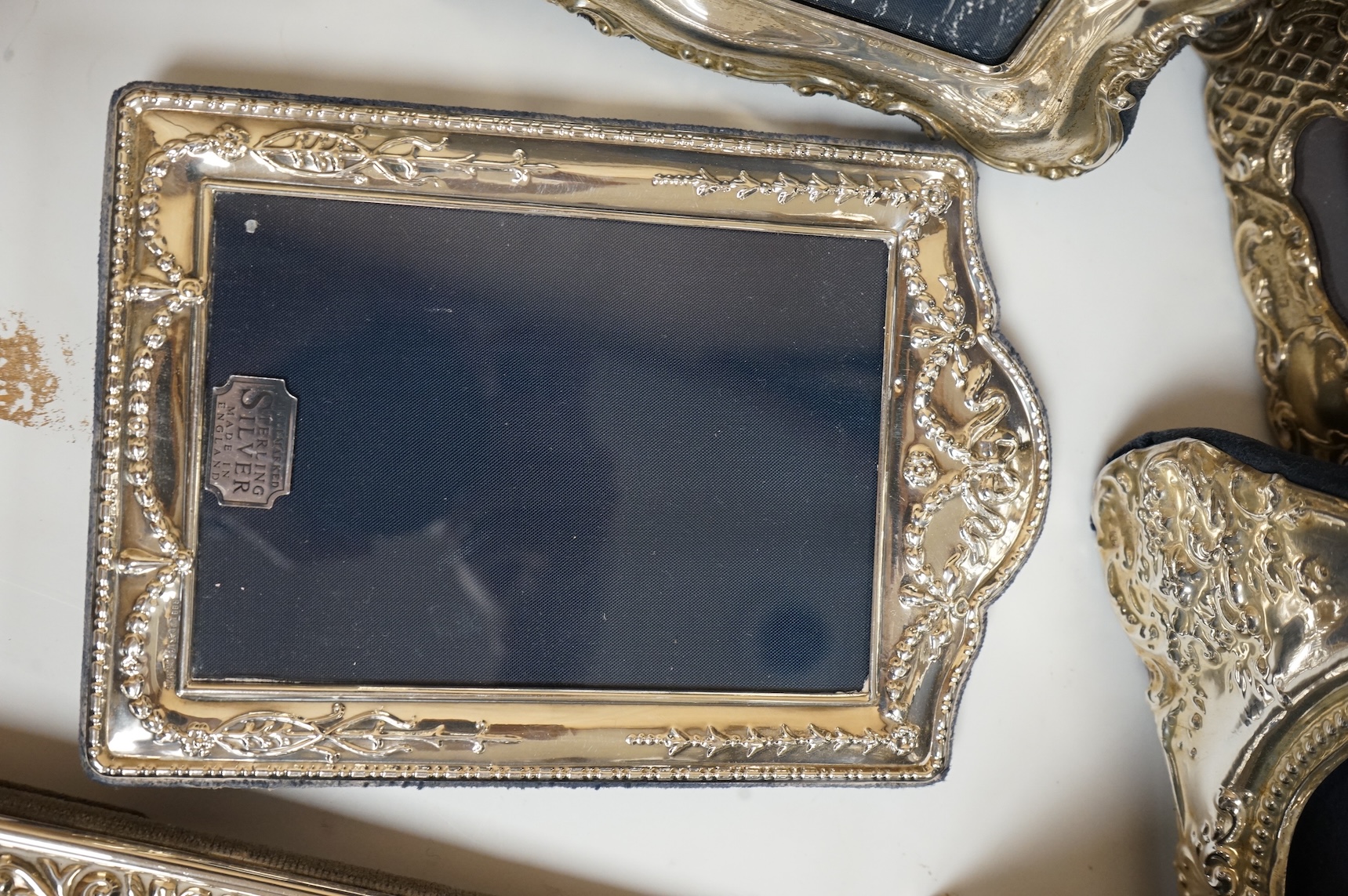 A George V silver mounted rectangular photograph frame, with ribbon bow crest, by Stokes & Ireland Ltd, Chester, 1912, 18.2cm including crest, together with ten other modern silver mounted photograph frames, largest 29.4